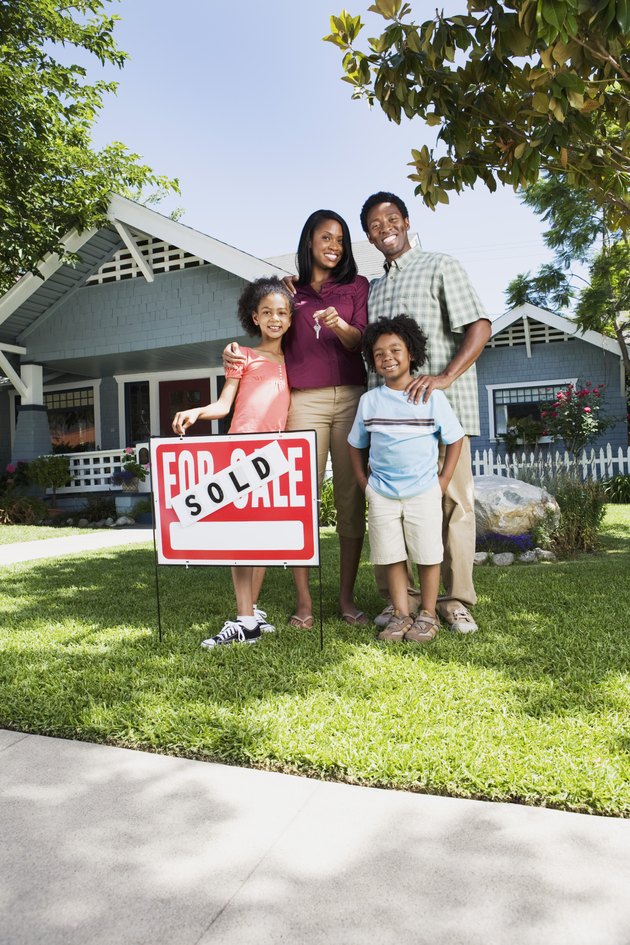 Family with sold sign in front of house