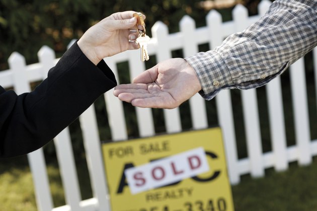 Hands of real estate agent handing over keys to new homeowner