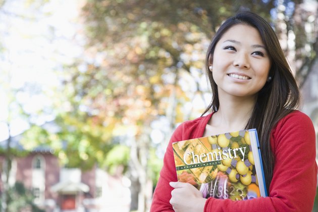Student holding a book and smiling