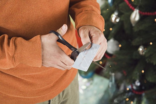 Man cutting credit card with scissors