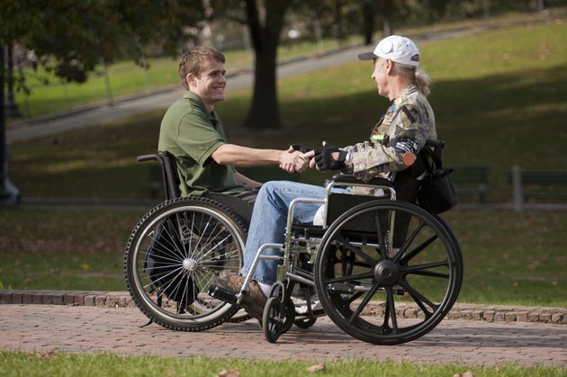 Two veterans shaking hands in wheelchairs
