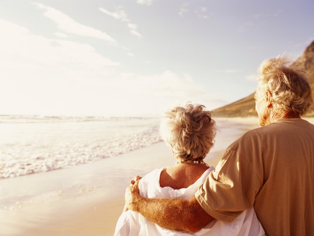 Senior couple embracing on beach, rear view