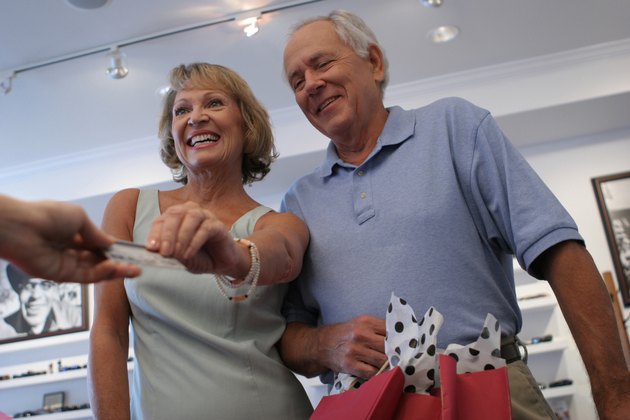Low angle view of a senior couple handing a credit card to a person