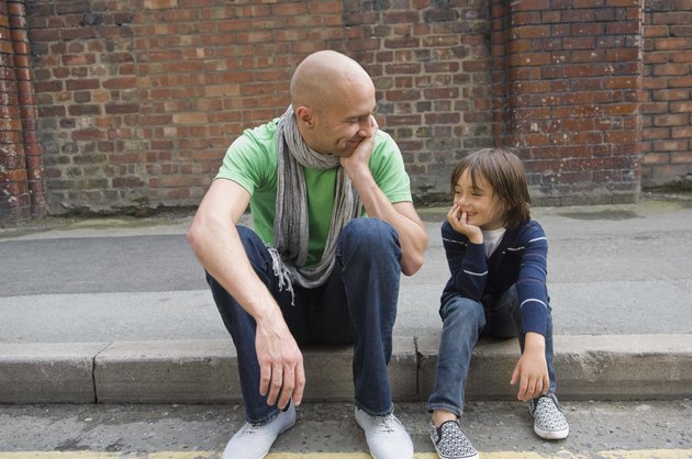 Father and son sitting on curb
