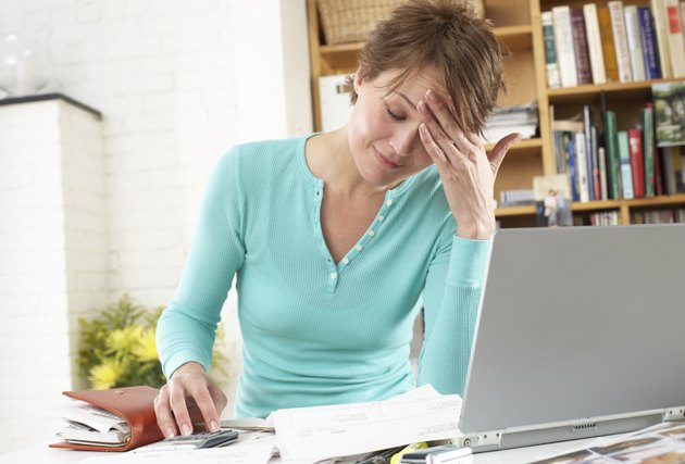 Woman by laptop in home office, hand on forehead
