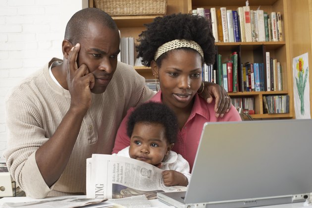Couple with baby girl (6-9 months), looking at laptop