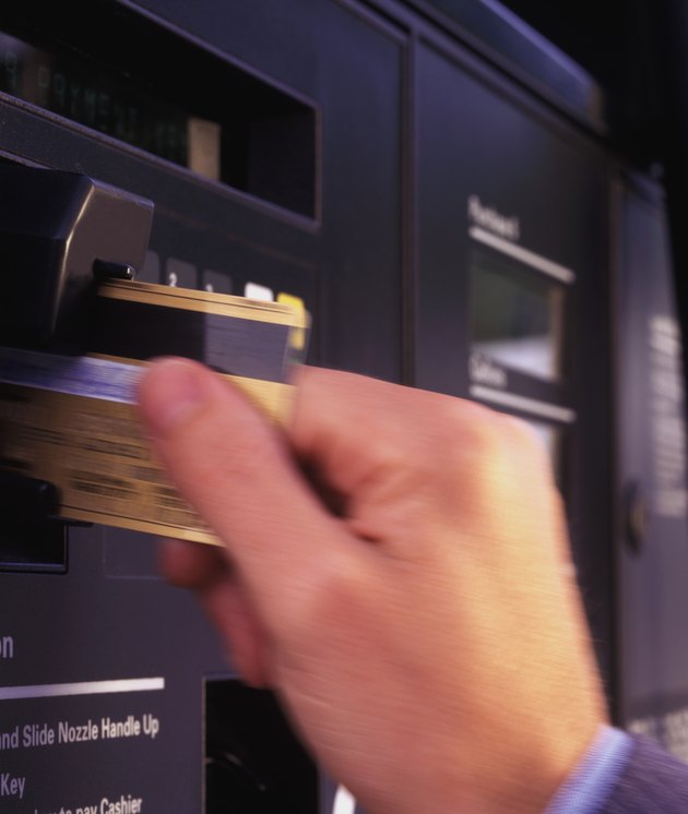 hand with credit card pumping gas