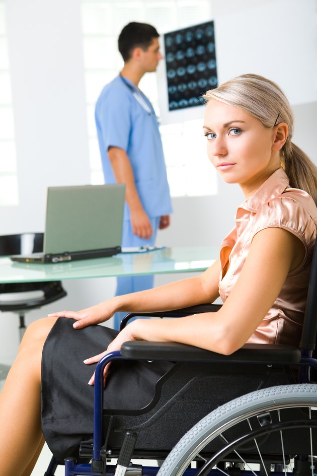 Woman in wheelchair with doctor analyzing imaging