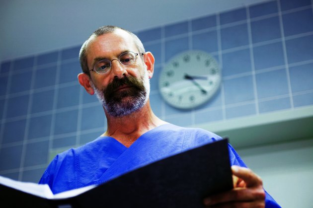 "Male surgeon in theatre, looking over notes, low angle view"