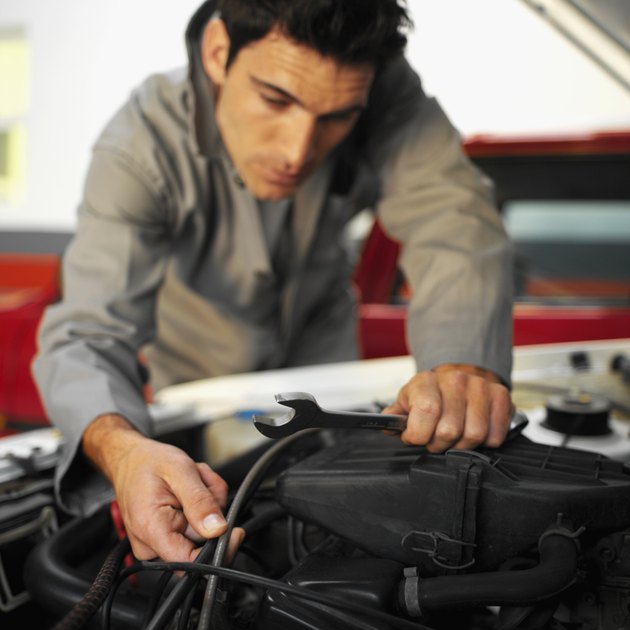 Close up of an car engine being repaired by a male mechanic holding a spanner