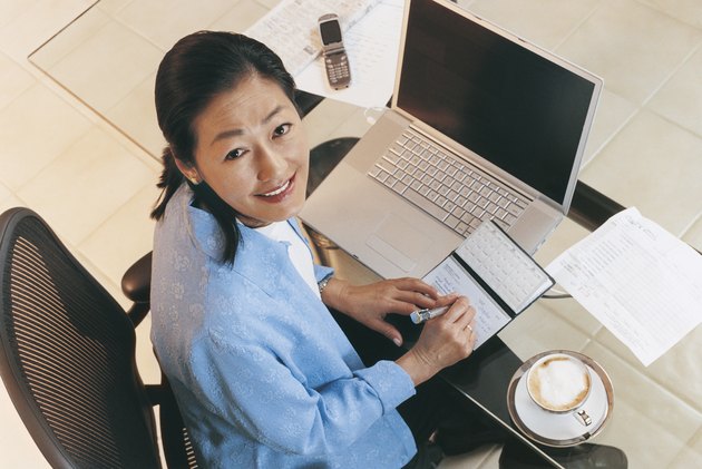 Portrait of a Mature Woman Sitting at a Desk and Writing Out a Cheque