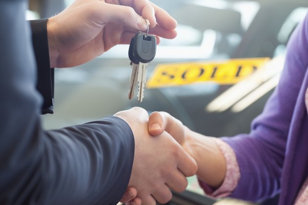 Person shaking hands in front of a sold car