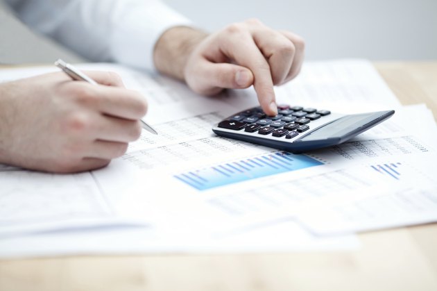 Financial data analyzing. Counting on calculator.