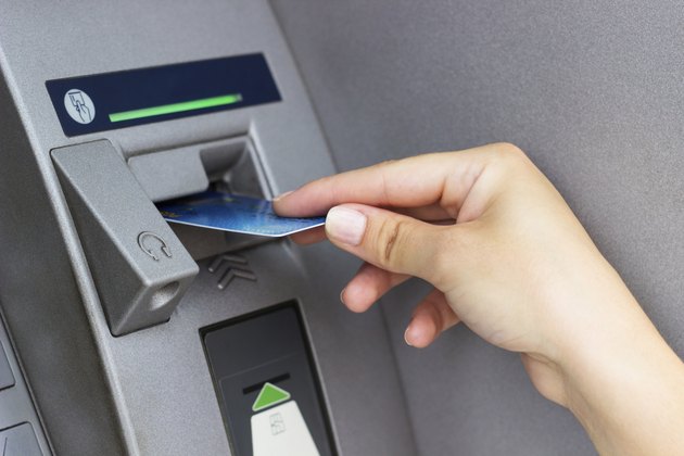 Woman's hand puts credit card into ATM