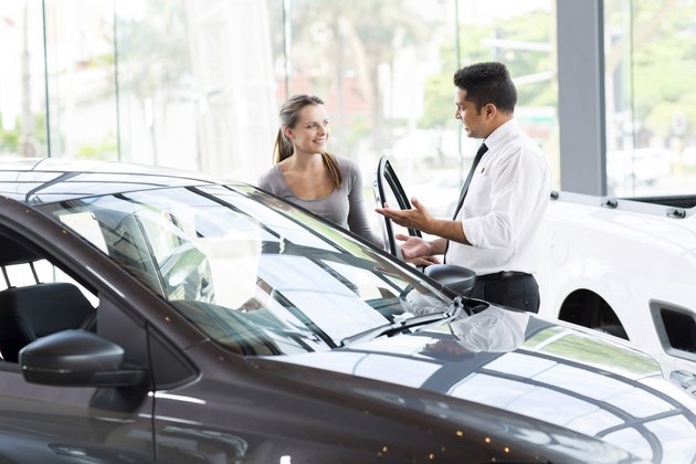 vehicle dealer showing young woman new car