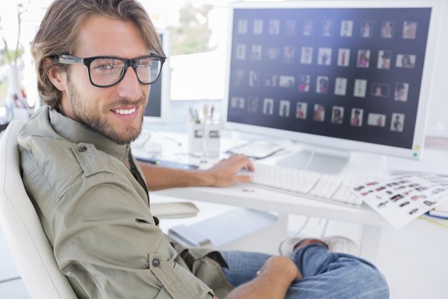 Photo editor turning and smiling at his desk