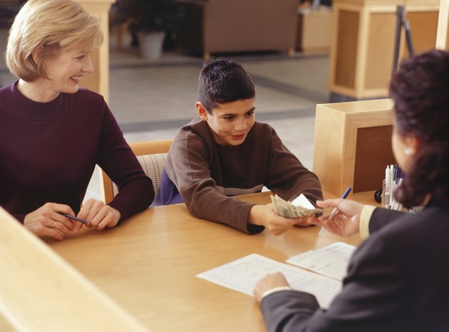 Teenage boy (13-14) giving money to bank teller