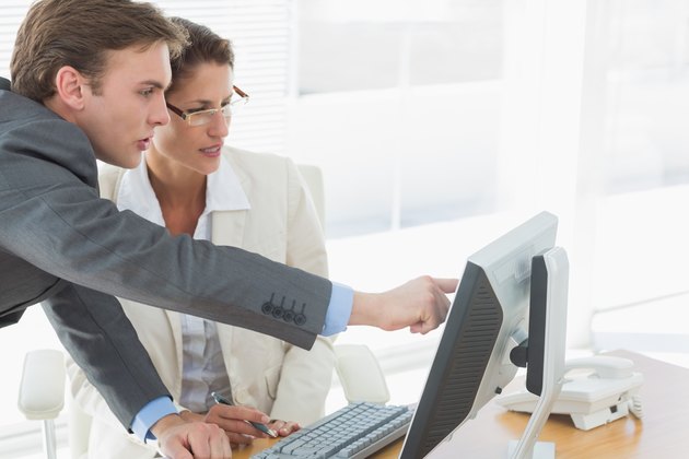 Business couple using computer at office desk