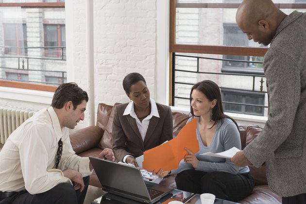 Businesspeople looking at documents and laptop