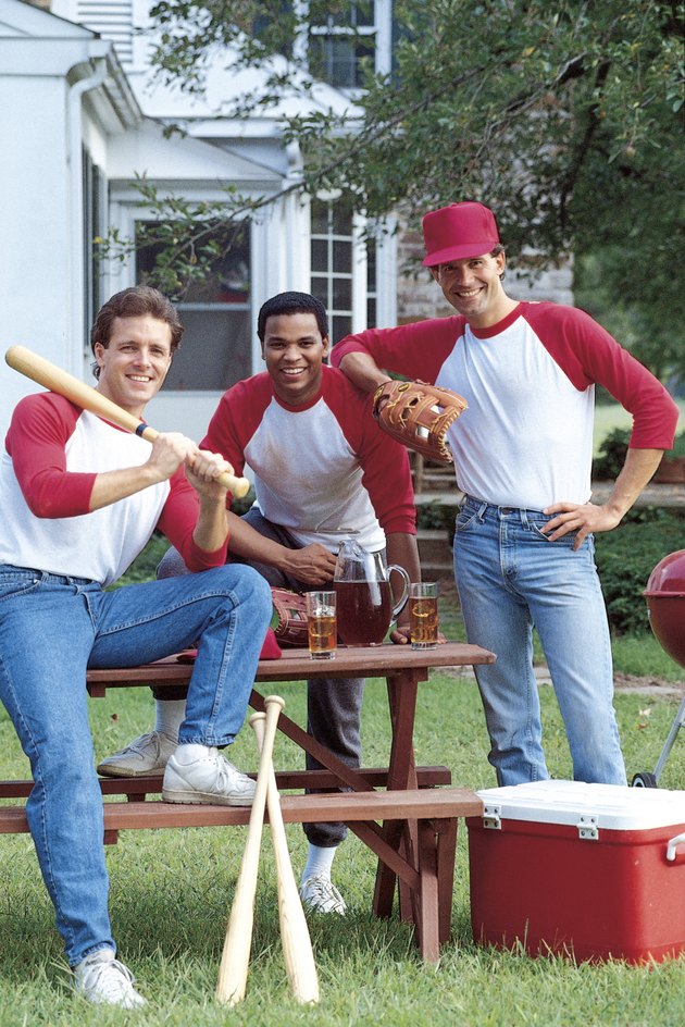 Men with baseball gear posing in backyard
