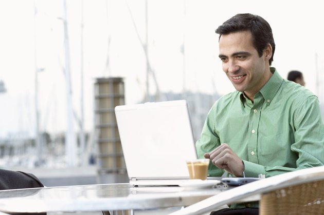Businessman sitting at table outdoors using laptop