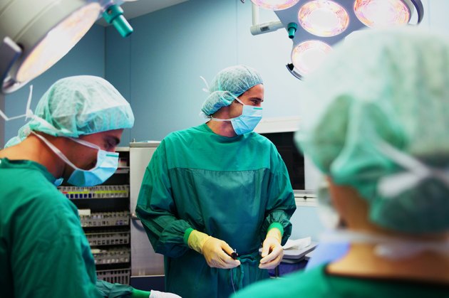 Operating theatre team tending to patient, surgeon looking to side