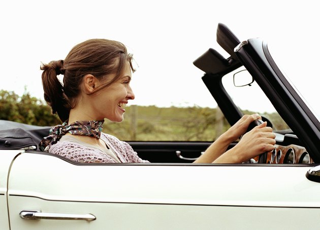 Young woman driving car, smiling, side view