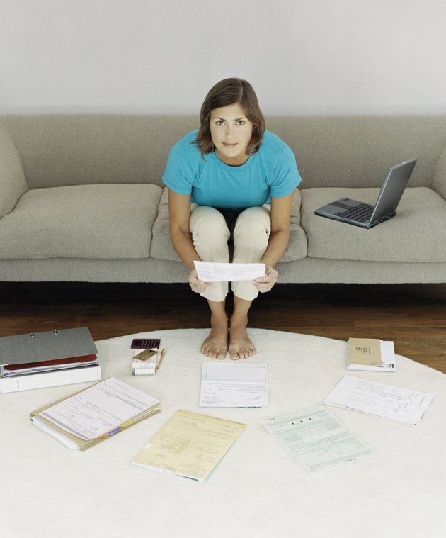 Elevated View of a Woman Sitting on a Sofa Surrounded by Bills