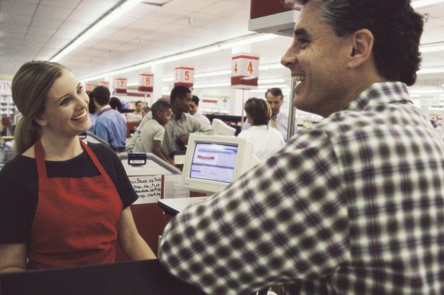 Female sales clerk talking to a customer at the checkout counter in a supermarket