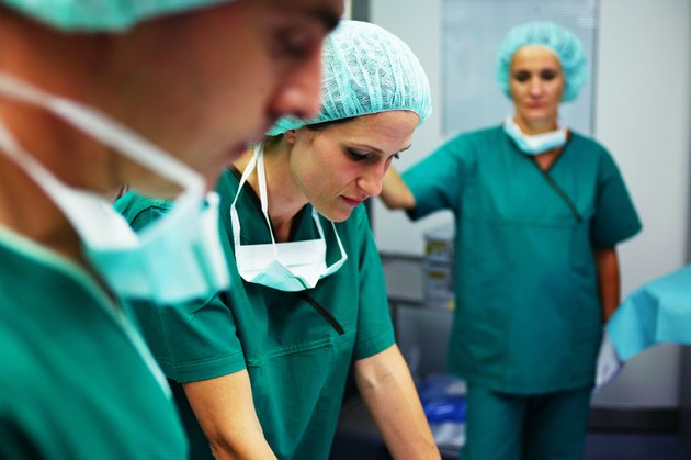 Operating theatre staff wearing scrubs in theatre (focus on woman)