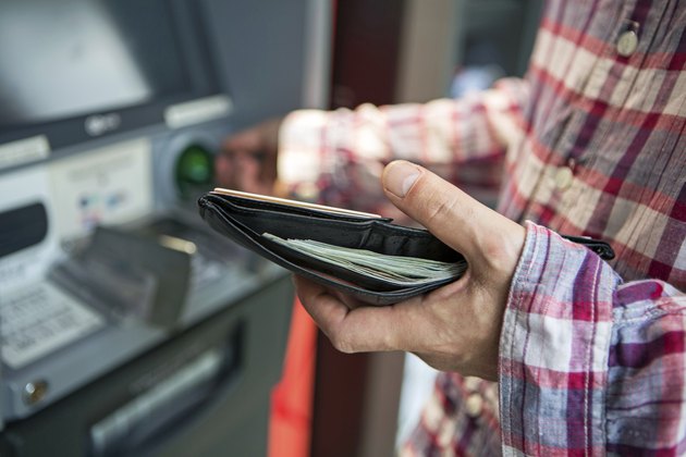 Man withdrawing money from ATM with focus on wallet