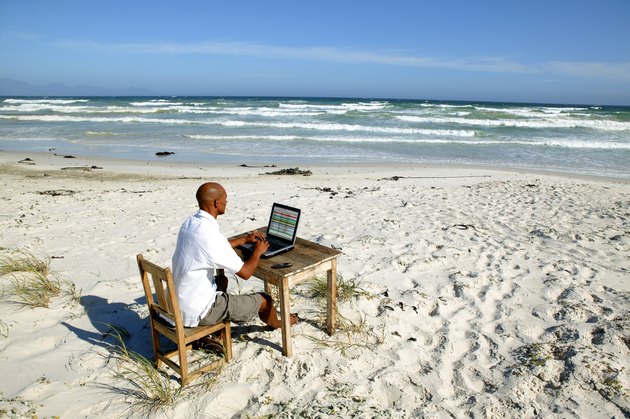 Dark-skinned bald man working at his desk on the beach