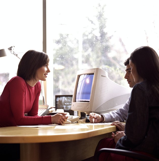 Young couple meeting with woman at desk, side view