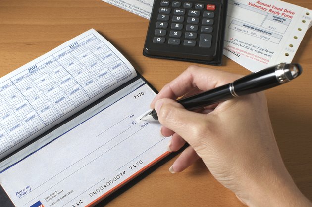 "Writing a check to pay the bills, hand holding pen"