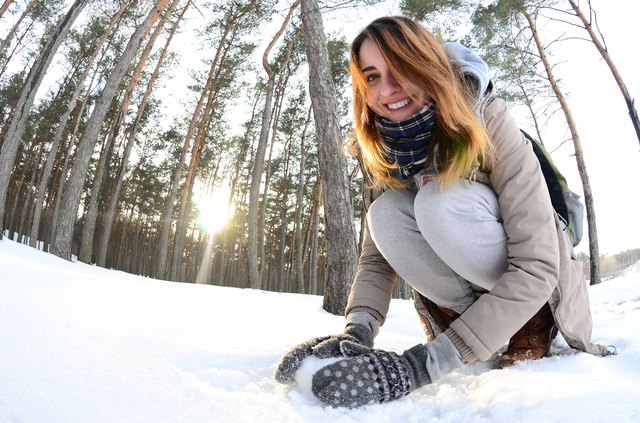 Young woman making a snowball in a forest