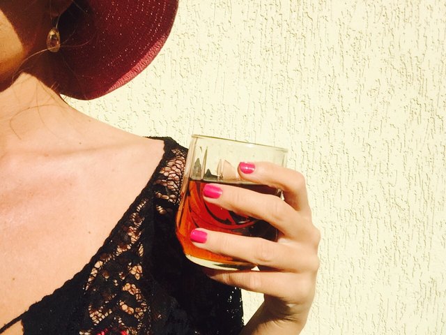 Woman with pink nail polish holding glass of whiskey