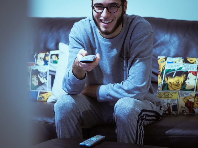 Young white man using remote control and smiling