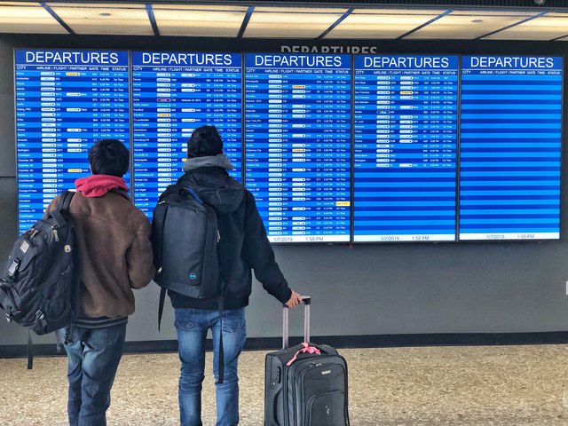 Two travelers looking at airport departures board