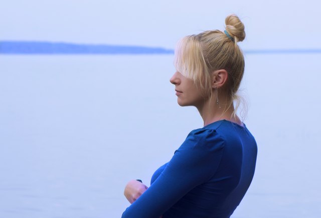 Blond woman in blue top looking out over water