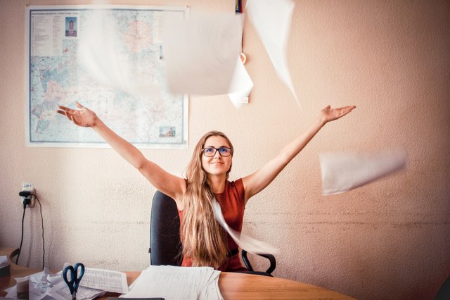 Woman at desk tossing papers in the air