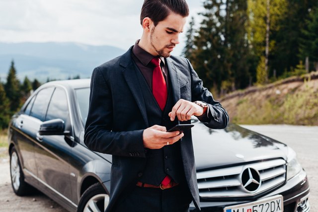 Stylish young man in suit poses in front of BMW