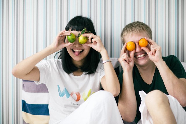 Cute interracial couple holding citrus fruit over eyes