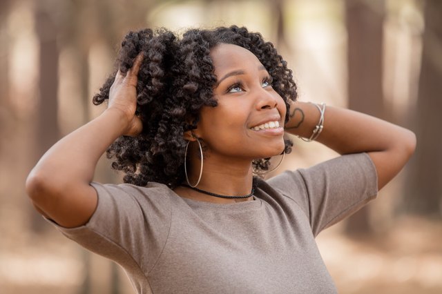Young Black woman smiling in wooded area