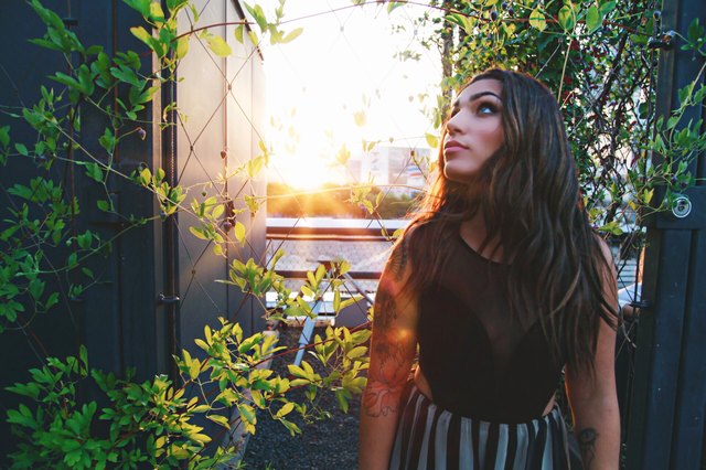 Woman amid rooftop vines at golden hour