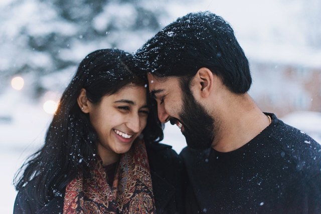 South Asian couple cuddling in the snow
