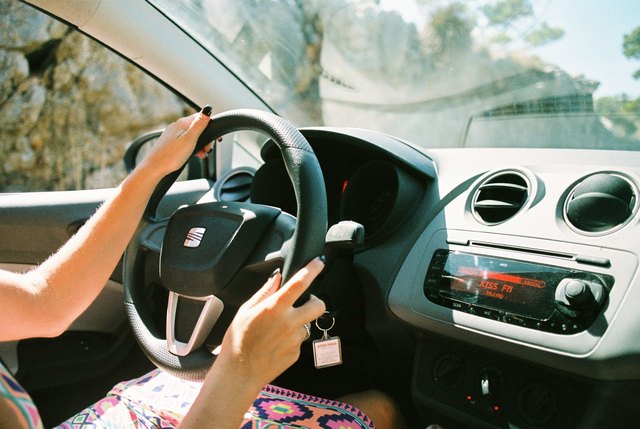 Woman's hands on steering wheel of sunny car