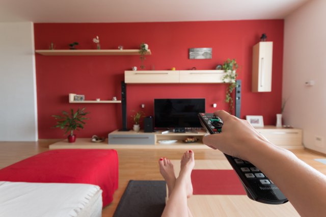 POV turning on TV with remote in red room
