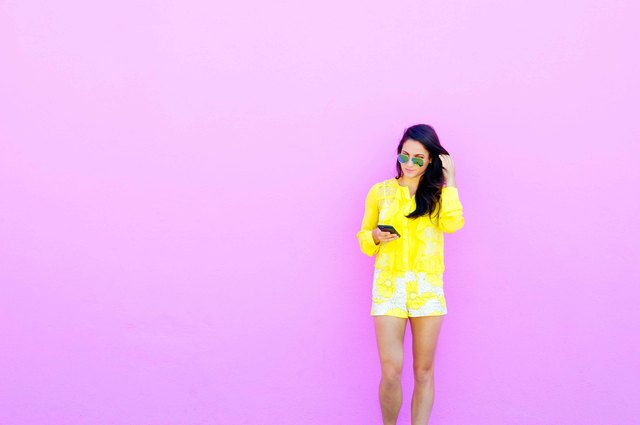 Young woman in yellow outfit standing against purple wall