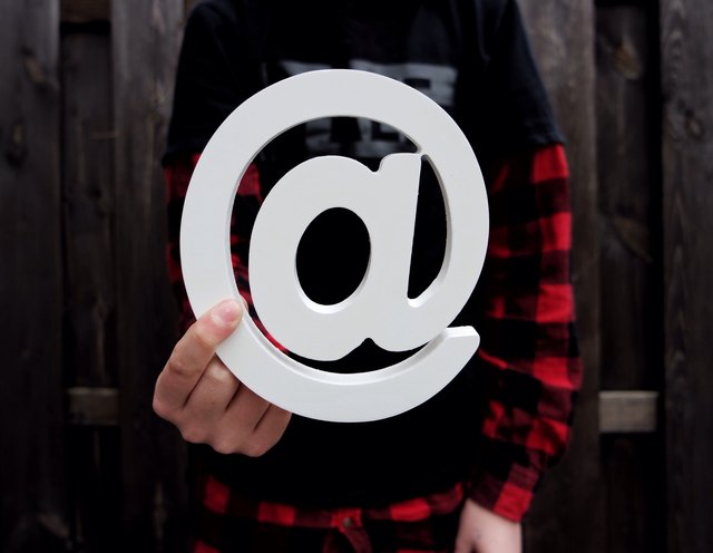 Person holding white at-symbol (@)