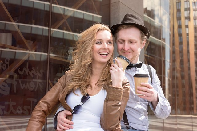 Odd couple cuddling with to-go coffee cups